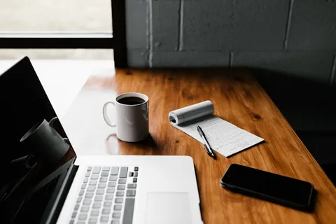 Postazione di lavoro con laptop, caffè e appunti